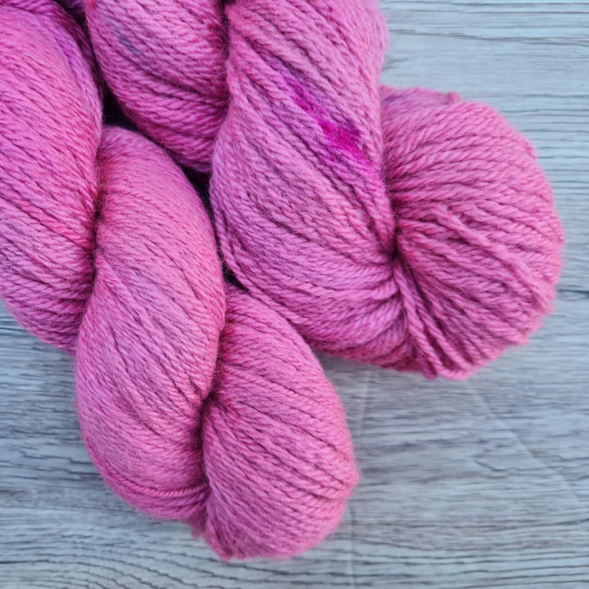 A close up of two skeins of pink tonal yarn.